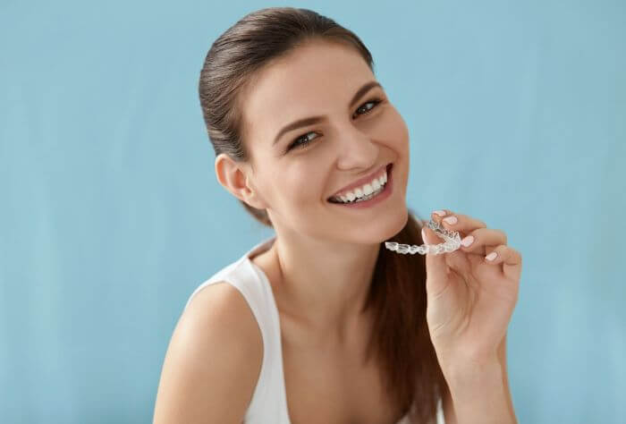 woman holding invisalign aligners whilst smiling