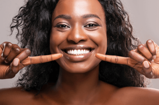 woman with composite bonding pointing to her teeth smiling