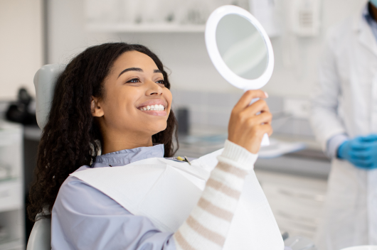 girl with straight white teeth smiling at mirror