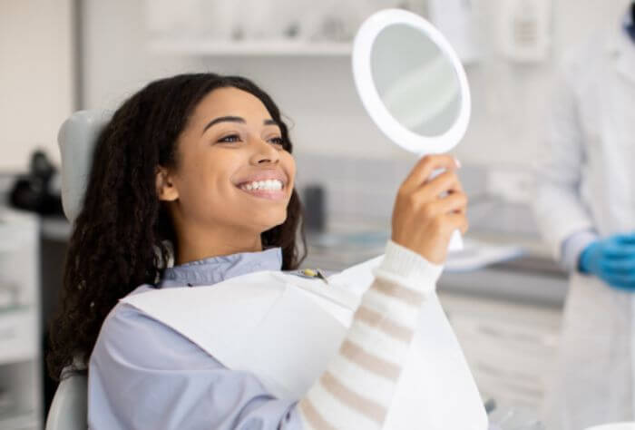 girl with straight white teeth smiling at mirror after Composite bonding