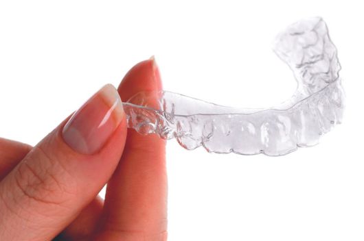 Hand holding invisalign aligners against a white background